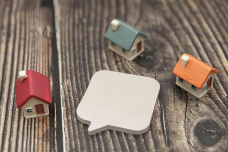 Several colored houses and paper stickers on a wooden background.